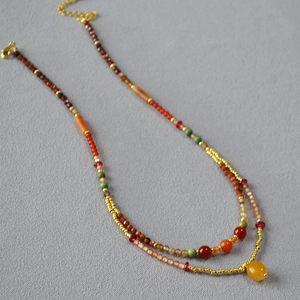 Close-up of a double-layered beaded necklace with colorful stones and gold lobster clasp
