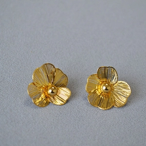 Detailed view of gold hollow flower earrings with delicate brushed metal texture
