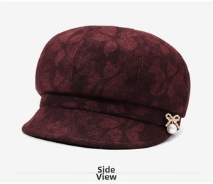 Detail of burgundy newsboy hat with jacquard pattern and pearl rhinestone bow pin