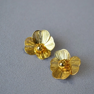 Detailed macro view of golden double-layered hollow flower earrings with central pearl studs