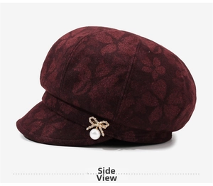 Detail view of burgundy floral jacquard newsboy hat with pearl and bow ornament