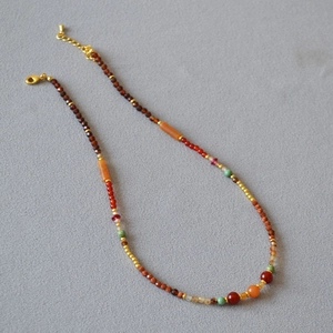 Detail of bohemian layered necklace with red-brown beads and gold adjustable chain