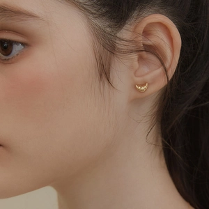 Close-up of gold-plated croissant stud earrings featuring delicate textured metal stripes