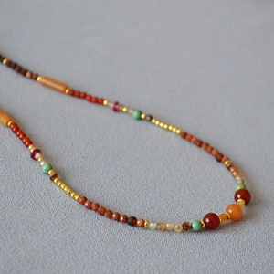 Close-up of double-layer beaded necklace with red agate, turquoise, and gold spacers