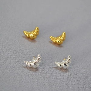 Macro view of gold and silver croissant-shaped stud earrings with spiral texture