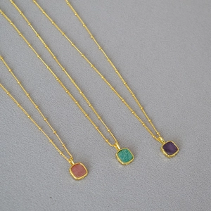 Detailed view of three colorful square stone pendants on golden beaded satellite chains