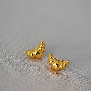 Macro shot of gold-plated croissant stud earrings featuring a polished vintage finish
