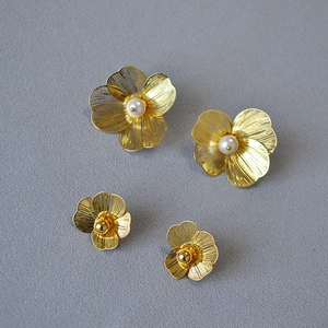 Close-up of double-layered floral stud earrings with pearls and gold wire petals