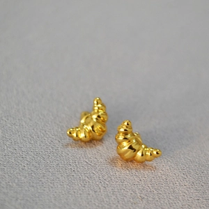 Close-up of golden croissant earrings with fine spiral texture and polished finish
