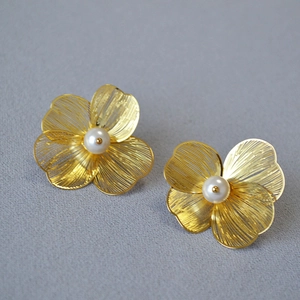 Detail of golden double-layer hollow flower earrings with brushed metal and pearls