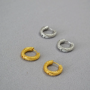 Detailed view of twisted rope texture on gold and silver round hoop earrings