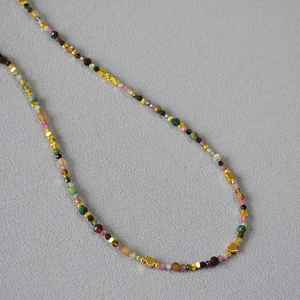 Detail of colorful faceted tourmaline beads with gold heart pendants on a necklace