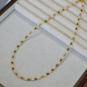 Close-up of elegant beaded necklace featuring pearls, colorful stones and gold textured beads