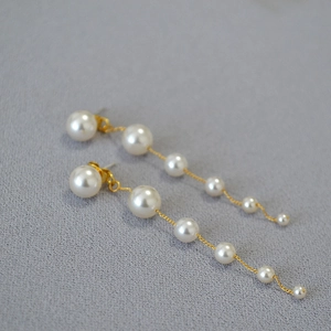 Detailed macro view of long tassel earrings with gradient white pearls and gold chains
