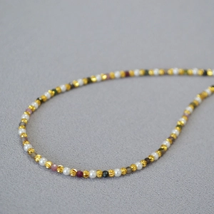 Macro detail of French style beaded necklace with gold beads, pearls and tourmaline