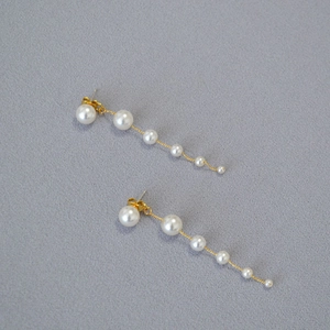 Macro view of gradient white pearls and gold metal chain on drop earrings