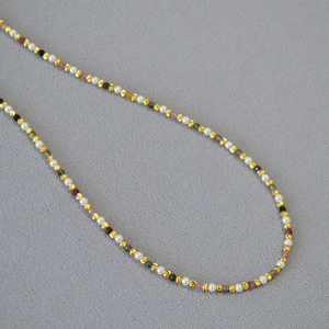 Detailed close-up of colorful tourmaline beads and pearls on a fine gold-plated necklace