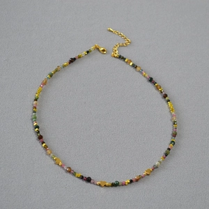 Detail of colorful tourmaline beaded necklace featuring golden heart accents and lobster clasp