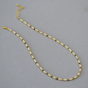 Detail of beaded necklace featuring colorful gemstones, pearls and gold chain