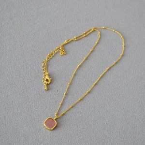 Detail of gold satellite chain with square pink gemstone pendant and lobster clasp closure