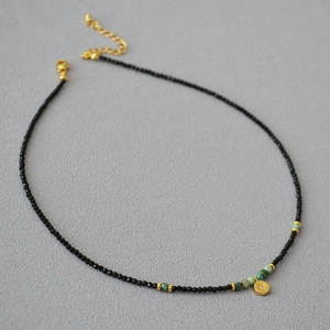 Detail of beaded necklace with black spinel, turquoise beads and a gold star pendant