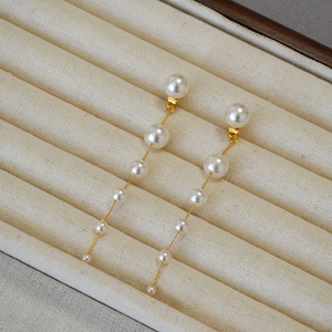 Detail of gradient pearl tassel earrings on gold chain with elegant soft luster