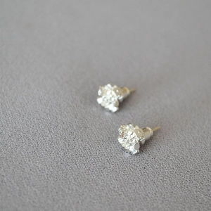 Detailed close-up of silver-tone crystal cluster studs on textured grey fabric