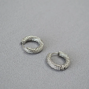 Macro detail of silver twisted rope textured hoop earrings with a secure clasp closure
