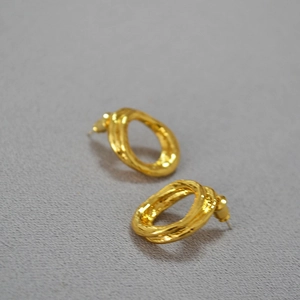 Close-up of golden irregular textured hoop earrings with a minimalist molten design