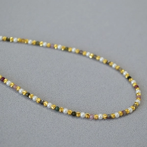 Detailed macro view of delicate beaded necklace with gold textured beads and pearls
