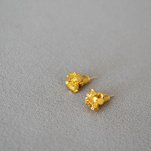 Macro detail of gold-plated irregular crystal cluster studs with metallic texture