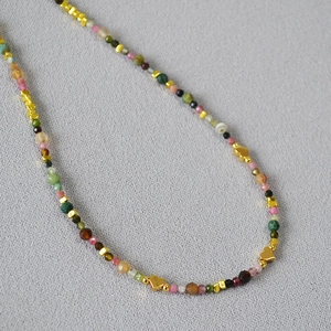 Close-up of colorful tourmaline beads with gold heart charms on a choker necklace