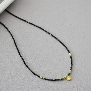 Detailed macro view of black spinel beaded necklace with gold star coin pendant charm
