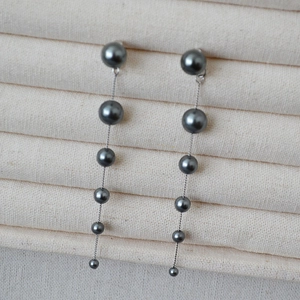 Detail of long linear tassel earrings with gradient dark grey pearls on silver chain