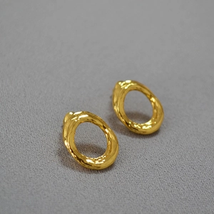 Detail of irregular textured gold hoop earrings with a modern hammered lava-like surface