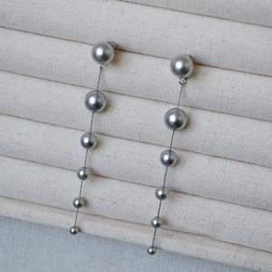 Detail of elegant gradient pearl tassel drop earrings with long silver chains on a display box