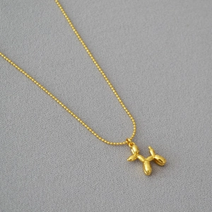Vue détaillée d'un pendentif chien ballon doré sur une chaîne à billes délicate