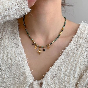 Detail of turquoise beaded necklace with golden moon and star pendants on a model