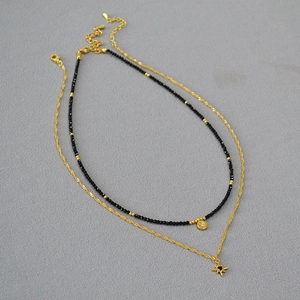 Close-up of double layer gold chains with black spinel beads and star pendants