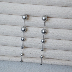 Close-up of long linear earrings with dark grey gradient pearls on S925 silver needles