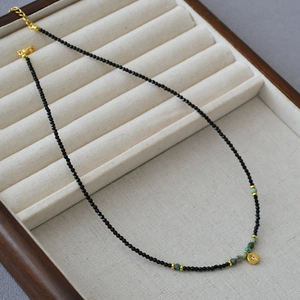 Detailed macro of black spinel bead necklace with turquoise and star engraved gold pendant