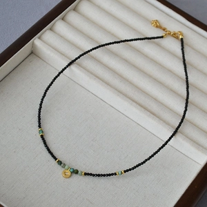 Detail of beaded black spinel necklace with turquoise and gold star medallion pendant