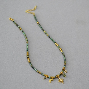 Turquoise beaded necklace featuring moon, star, and gemstone pendants on a grey background