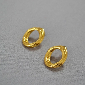 Close-up of gold-plated hoop earrings featuring irregular lava texture and artistic design