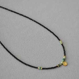 Macro detail of beaded necklace with black spinel, turquoise accents and star gold pendant