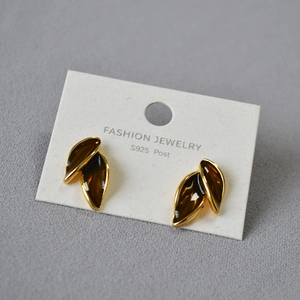 Detail of amber enamel leaf earrings with S925 silver posts in a golden metal frame