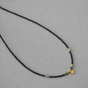 Close-up of beaded necklace with black spinel, turquoise accents, and star pendant