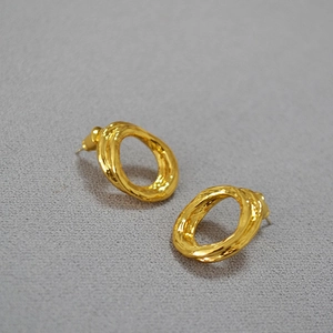 Detailed macro shot of gold plated earrings featuring a unique molten lava texture design