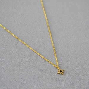 Detail of gold star pendant with black center stone on a double layer twist chain