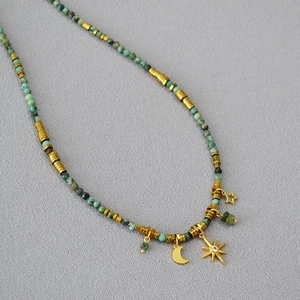 Detail of bohemian turquoise beads with gold moon and north star charms on a necklace